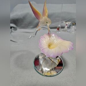 Glass Baron hummingbird figurine with a flower on a mirrored base. 